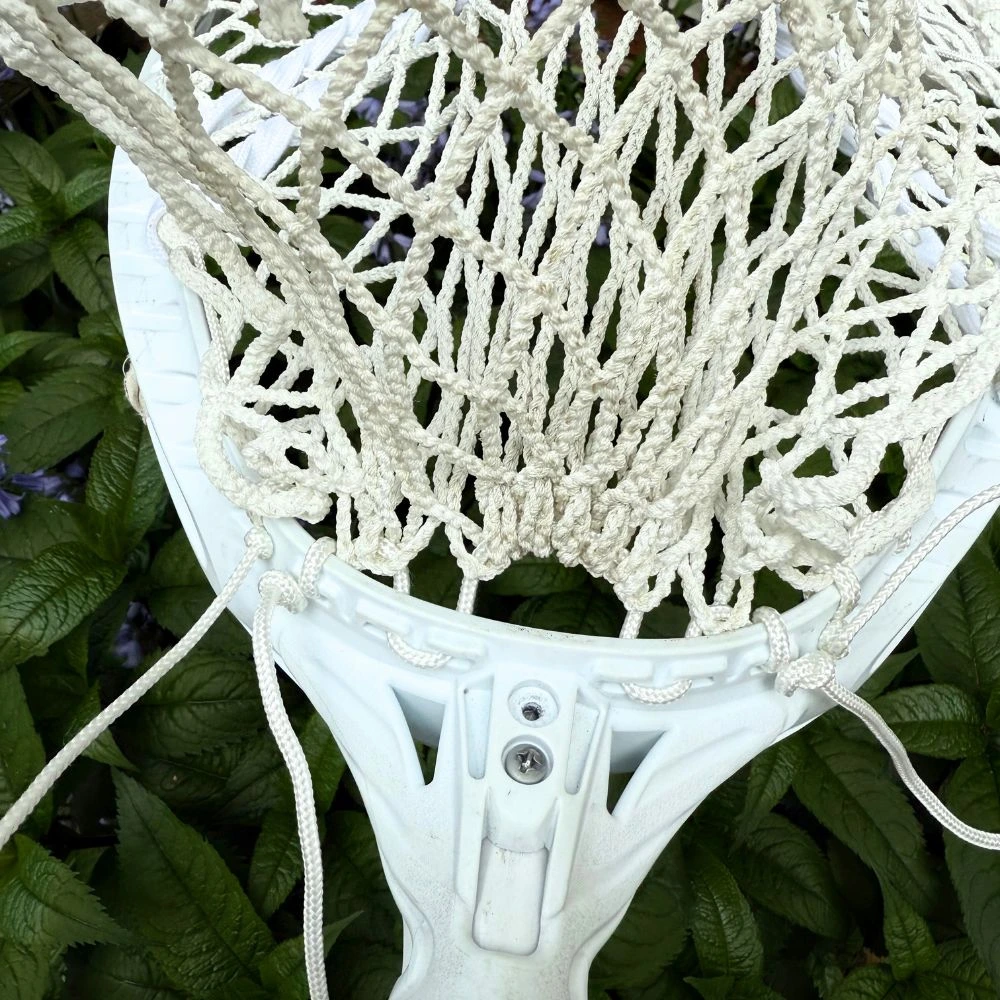 Close-up of the white StringKing Grizzly 2 mesh pocket strung into a white STX Eclipse II lacrosse goalie head, highlighting the bottom string