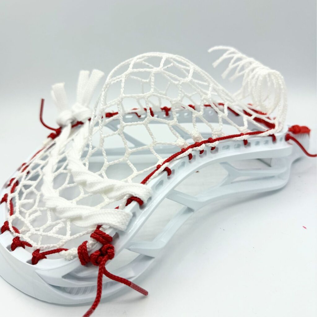STX Magnet 2k lacrosse head strung with ECD Hero 4.0 7-diamond mesh and red sidewall string — angled side view showing pocket depth