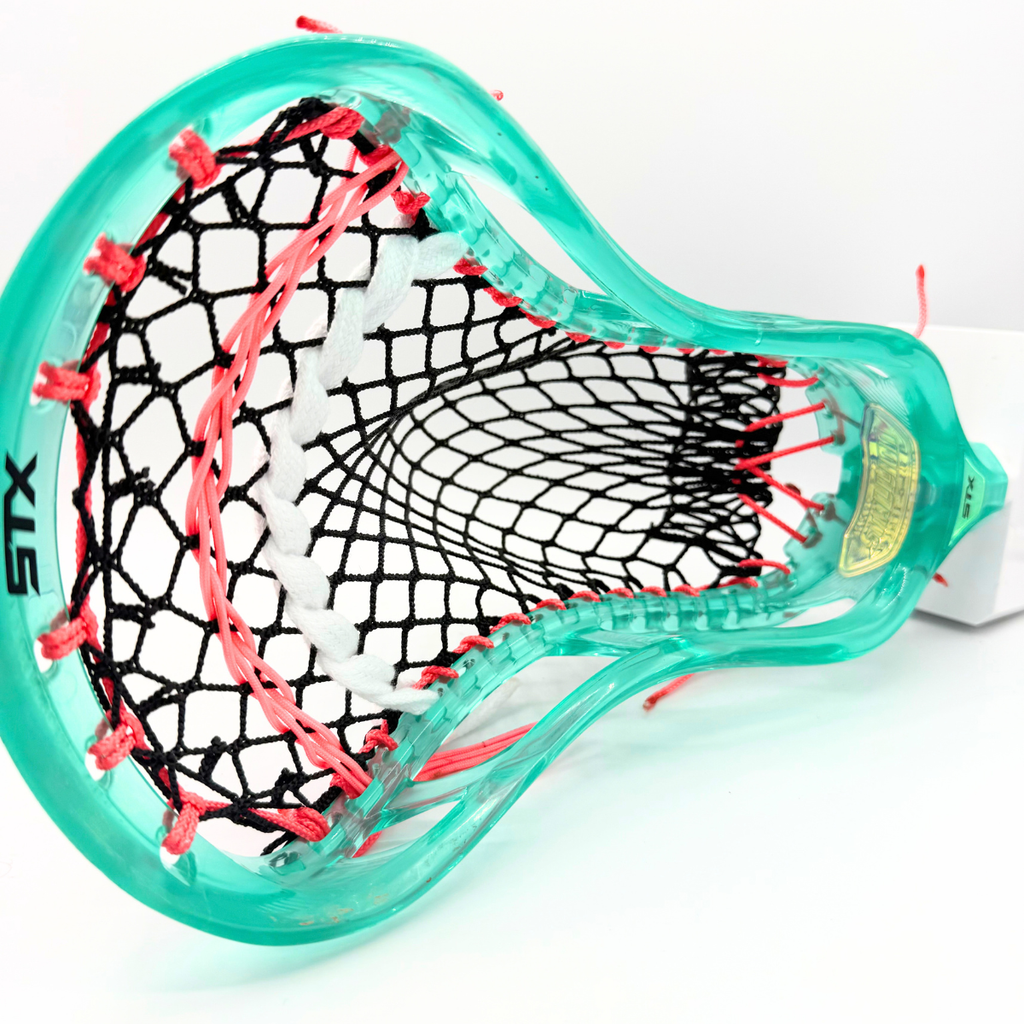 angled view of stx stallion prism mid pocket with black g3 xl mesh, coral pink shooting strings, and a white lace shooter