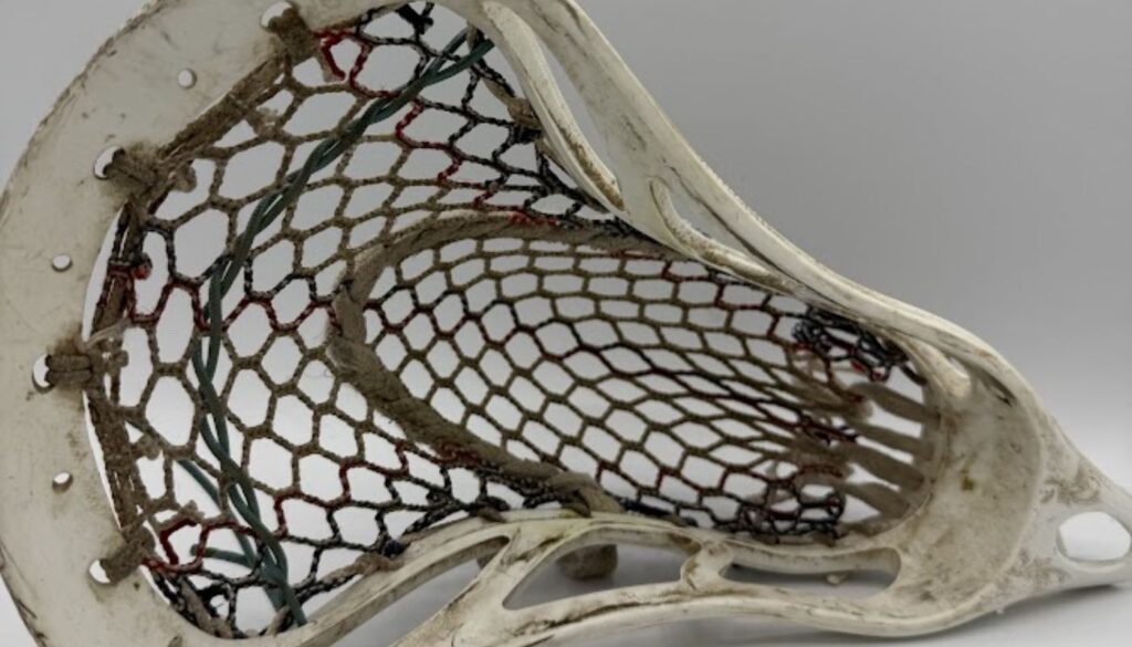 lacrosse stick with worn mesh and loose sidewalls showing signs it needs to be restrung