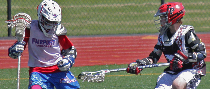 youth lacrosse defender guarding a youth lacrosse attackman